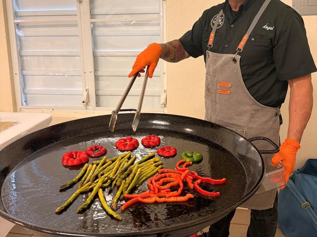 El chef Ángel con su delantal A&K y la paellera con pimientos y espárragos listos