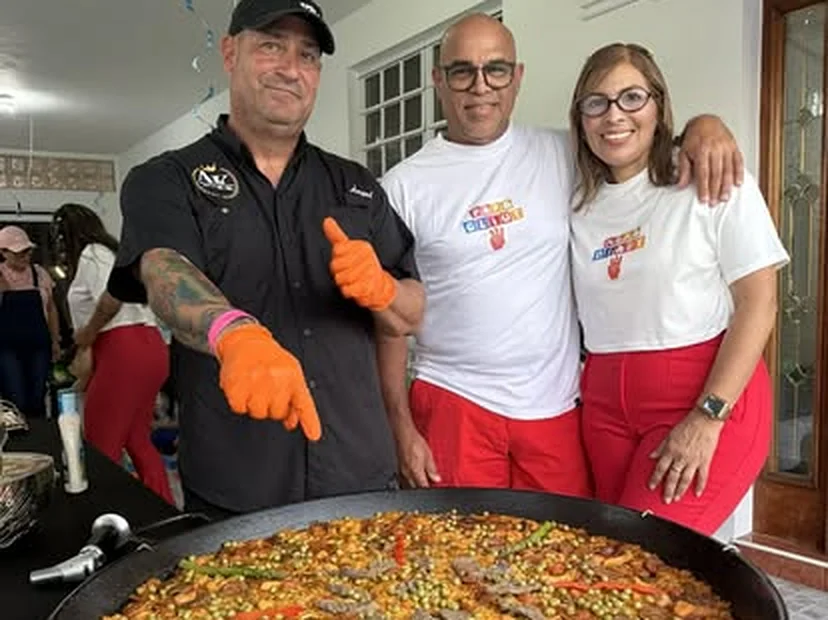 El chef Ángel posando con dos clientes detrás de una paella recién hecha